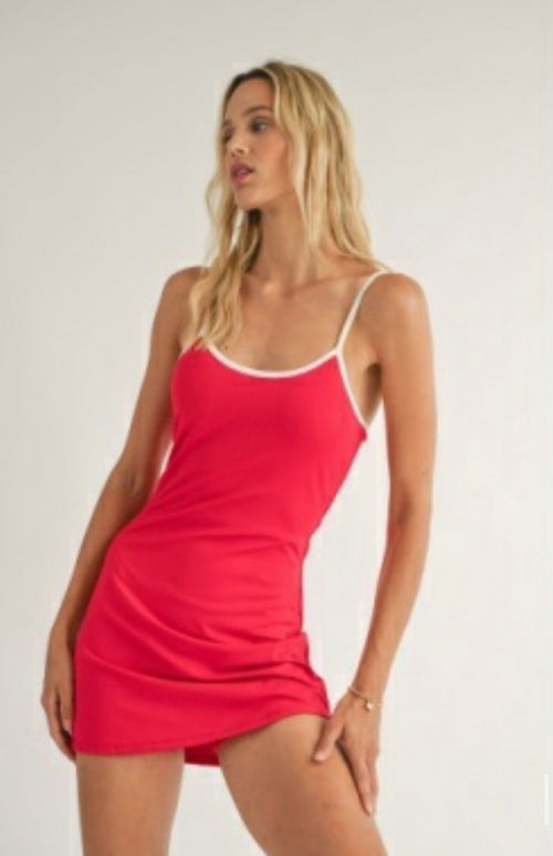 Sadie and Sage model wearing Courtside Lined Romper, cherry red bodycon short dress, spaghetti straps with white detail, dress ends a little before mid thigh. Features shorts underneath a dress appearance.